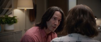 Movie still from “Bill & Ted Face the Music” (2020), directed by Dean Parisot – A man with long black hair and a pink shirt; Close Up shot, Over the shoulder angle