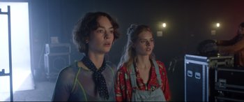 Movie still from “Bill & Ted Face the Music” (2020), directed by Dean Parisot – Two young women standing next to each other in a dark room; Medium shot, Low angle