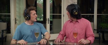 Movie still from “Bill & Ted Face the Music” (2020), directed by Dean Parisot – Two men sitting at a table with wine glasses and headphones on; Medium shot, Over the shoulder angle