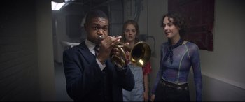 Movie still from “Bill & Ted Face the Music” (2020), directed by Dean Parisot – A man playing a trumpet in front of two other people; Medium shot, Low angle