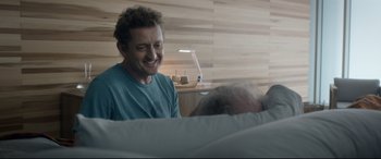 Movie still from “Bill & Ted Face the Music” (2020), directed by Dean Parisot – A man sitting in a hospital bed smiling; Medium shot, Over the shoulder angle