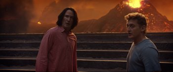 Movie still from “Bill & Ted Face the Music” (2020), directed by Dean Parisot – A man standing in front of some steps in front of a mountain range; Medium shot, Over the shoulder angle