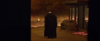 Movie still from “Bill & Ted Face the Music” (2020), directed by Dean Parisot – A man in a black robe standing in front of a fire; Wide shot, Over the shoulder angle