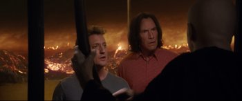 Movie still from “Bill & Ted Face the Music” (2020), directed by Dean Parisot – Two men standing next to each other in front of a fire background; Medium shot, Over the shoulder angle