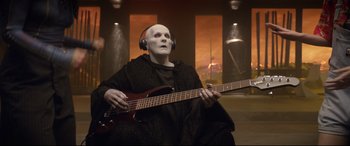 Movie still from “Bill & Ted Face the Music” (2020), directed by Dean Parisot – A person with a face mask on holding a guitar; Medium shot, Low angle