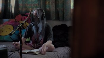 Movie still from “Billie Eilish: The World's a Little Blurry” (2021), directed by R.J. Cutler – A person with a microphone and headphones on; Medium shot, High angle