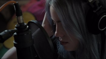 Movie still from “Billie Eilish: The World's a Little Blurry” (2021), directed by R.J. Cutler – A woman with grey hair is listening to a microphone; Close Up shot, Low angle