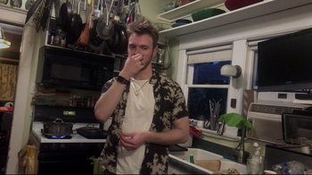 Movie still from “Billie Eilish: The World's a Little Blurry” (2021), directed by R.J. Cutler – A man in a kitchen eating something off a spoon; Medium shot, Low angle