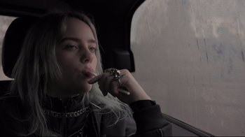 Movie still from “Billie Eilish: The World's a Little Blurry” (2021), directed by R.J. Cutler – A woman sitting in the back seat of a car; Close Up shot, Low angle
