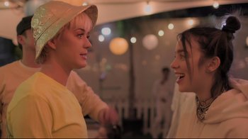 Movie still from “Billie Eilish: The World's a Little Blurry” (2021), directed by R.J. Cutler – Two people talking to each other at a party; Close Up shot, Over the shoulder angle