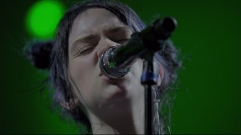 Movie still from “Billie Eilish: The World's a Little Blurry” (2021), directed by R.J. Cutler – A person that is holding a microphone up to their mouth; Close Up shot, Low angle