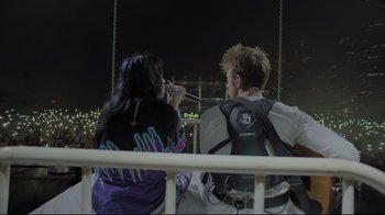 Movie still from “Billie Eilish: The World's a Little Blurry” (2021), directed by R.J. Cutler – A man and a woman sitting next to each other on a swing; Wide shot, Overhead angle