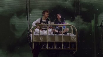 Movie still from “Billie Eilish: The World's a Little Blurry” (2021), directed by R.J. Cutler – A man and a woman sitting on a bed; Wide shot, Low angle