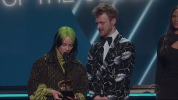 Movie still from “Billie Eilish: The World's a Little Blurry” (2021), directed by R.J. Cutler – A man and a woman standing next to each other holding a microphone; Medium shot, Low angle