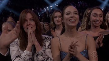 Movie still from “Billie Eilish: The World's a Little Blurry” (2021), directed by R.J. Cutler – A group of people sitting in front of an audience clapping; Medium shot, Low angle