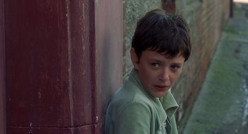 Movie still from “Billy Elliot” (2000), directed by Stephen Daldry – A young boy leaning up against a wooden wall; Close Up shot, Over the shoulder angle