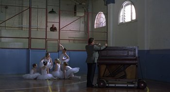 Movie still from “Billy Elliot” (2000), directed by Stephen Daldry – A group of young ballerinas and their teacher in a gymnasium; Wide shot, Low angle