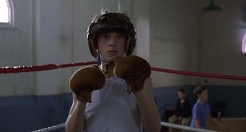 Movie still from “Billy Elliot” (2000), directed by Stephen Daldry – A young boy wearing a boxing helmet and gloves; Medium shot, Low angle