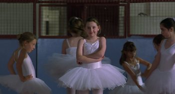 Movie still from “Billy Elliot” (2000), directed by Stephen Daldry – A little girl wearing a white tutu in front of other girls; Medium shot, Over the shoulder angle