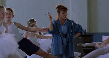 Movie still from “Billy Elliot” (2000), directed by Stephen Daldry – A woman holding a cigarette standing in front of a group of people; Medium shot, Over the shoulder angle