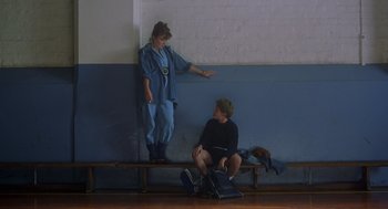 Movie still from “Billy Elliot” (2000), directed by Stephen Daldry – A man and a woman are sitting on a bench; Wide shot, Low angle