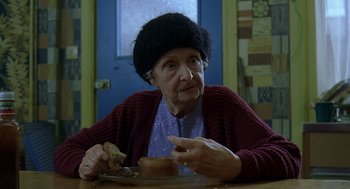Movie still from “Billy Elliot” (2000), directed by Stephen Daldry – An older woman sitting at a table with a piece of bread; Close Up shot, High angle