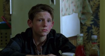 Movie still from “Billy Elliot” (2000), directed by Stephen Daldry – A young man sitting at a table looking at the camera; Close Up shot, Low angle