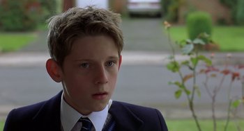 Movie still from “Billy Elliot” (2000), directed by Stephen Daldry – A boy in a suit and tie looking at the camera; Close Up shot, Low angle