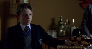 Movie still from “Billy Elliot” (2000), directed by Stephen Daldry – A boy in a suit and tie sitting at a bar; Close Up shot, Over the shoulder angle