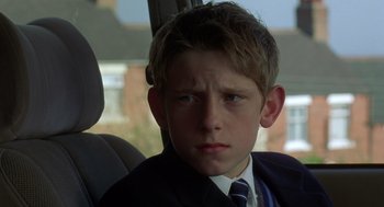 Movie still from “Billy Elliot” (2000), directed by Stephen Daldry – A boy in a suit and tie sitting in the back of a car; Close Up shot, Low angle