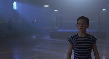 Movie still from “Billy Elliot” (2000), directed by Stephen Daldry – A person standing in a room with a light shining on them; Medium shot, Low angle