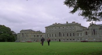 Movie still from “Billy Elliot” (2000), directed by Stephen Daldry – Two people are walking in front of a large building; Extreme Wide shot, Low angle