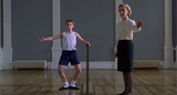 Movie still from “Billy Elliot” (2000), directed by Stephen Daldry – A woman standing next to a young boy in a room; Medium shot, Low angle