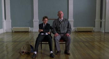 Movie still from “Billy Elliot” (2000), directed by Stephen Daldry – Two men sitting on chairs in a room; Wide shot, Low angle