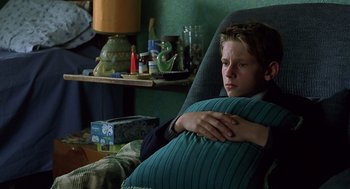 Movie still from “Billy Elliot” (2000), directed by Stephen Daldry – A young man sitting in a chair holding a pillow; Close Up shot, High angle