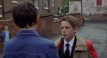 Movie still from “Billy Elliot” (2000), directed by Stephen Daldry – Two young men standing next to each other on the sidewalk; Medium shot, Over the shoulder angle