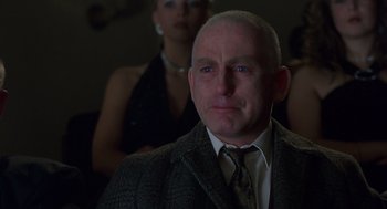 Movie still from “Billy Elliot” (2000), directed by Stephen Daldry – A man in a suit and tie with a woman behind him; Close Up shot, Low angle