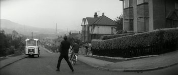 Movie still from “Billy Liar” (1963), directed by John Schlesinger – A man walking down the street with a bicycle; Extreme Wide shot, High angle