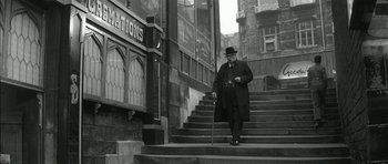 Movie still from “Billy Liar” (1963), directed by John Schlesinger – An old man walking down the steps of a building; Wide shot, Low angle