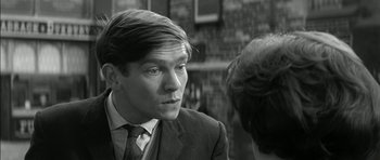 Movie still from “Billy Liar” (1963), directed by John Schlesinger – A man in a suit and tie looking at a woman in a dress suit; Close Up shot, Over the shoulder angle