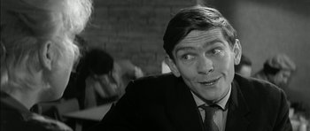 Movie still from “Billy Liar” (1963), directed by John Schlesinger – A man in a suit and tie with a smirking look on his face; Close Up shot, Over the shoulder angle