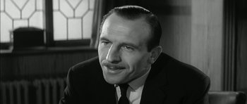 Movie still from “Billy Liar” (1963), directed by John Schlesinger – An older man in a suit and tie looking to his left; Close Up shot, Low angle