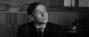 Movie still from “Billy Liar” (1963), directed by John Schlesinger – Black and white photograph of a man wearing a suit and tie; Close Up shot, Low angle