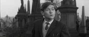 Movie still from “Billy Liar” (1963), directed by John Schlesinger – A black and white photo of a man in a suit and tie; Close Up shot, Low angle