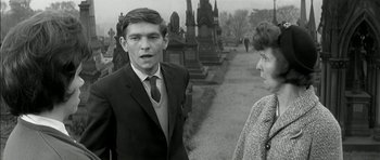 Movie still from “Billy Liar” (1963), directed by John Schlesinger – A man and a woman are standing in a cemetery; Medium shot, Over the shoulder angle