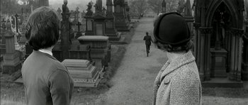 Movie still from “Billy Liar” (1963), directed by John Schlesinger – A man walking down a path in a cemetery; Medium shot, High angle