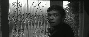 Movie still from “Billy Liar” (1963), directed by John Schlesinger – A black and white photo of a man in front of an iron gate; Close Up shot, Low angle