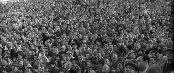 Movie still from “Billy Liar” (1963), directed by John Schlesinger – A large group of people sitting in a stadium; Wide shot, High angle