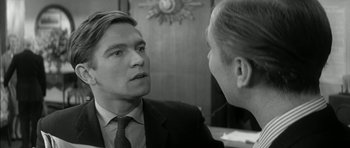 Movie still from “Billy Liar” (1963), directed by John Schlesinger – A man wearing a suit and tie talking to another man in a suit; Close Up shot, Over the shoulder angle