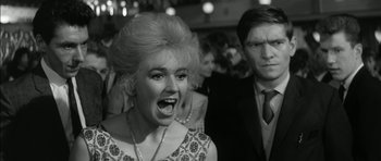 Movie still from “Billy Liar” (1963), directed by John Schlesinger – An old photo of a woman and a man at a party; Close Up shot, Low angle